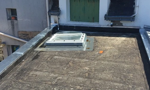 Ouvrier professionnel à genoux sur terrasse en bois appliquant une finition protectrice avec rouleau à peinture