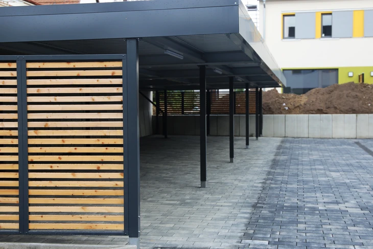 Espace extérieur couvert avec structure métallique noire supportant une toiture plate
