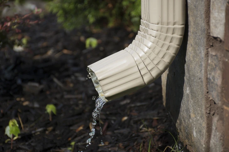 Scène extérieure montrant l'évacuation d'eau pluviale d'un bâtiment par gouttière en PVC blanc