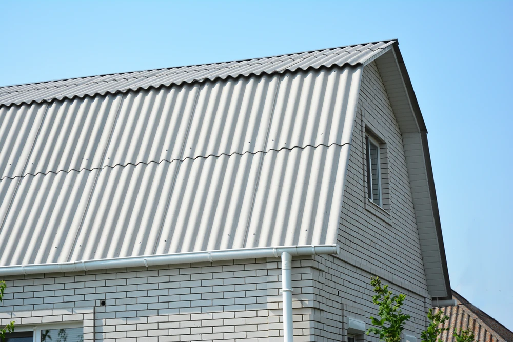 Extérieur d'une maison contemporaine sous ciel bleu dégagé, vue en contre-plongée sur la toiture et façade latérale