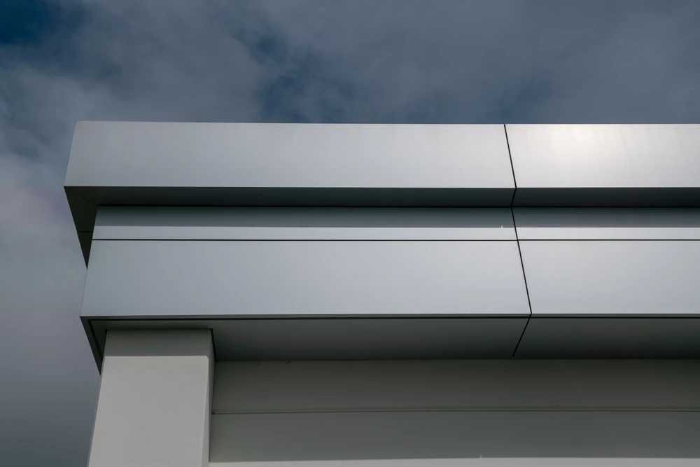 nouveau bâtiment avec toit plat et front métallique, le toit d'une maison, bâtiment avec toit incliné avec tuiles en briques, des feuilles visibles en tôle et devant de la corniche en acier galvanisé