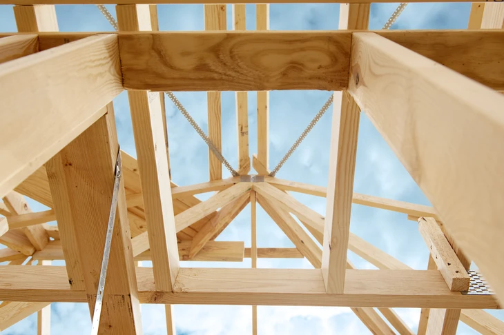 Chantier de construction résidentielle en cours, charpente bois apparente sous ciel bleu