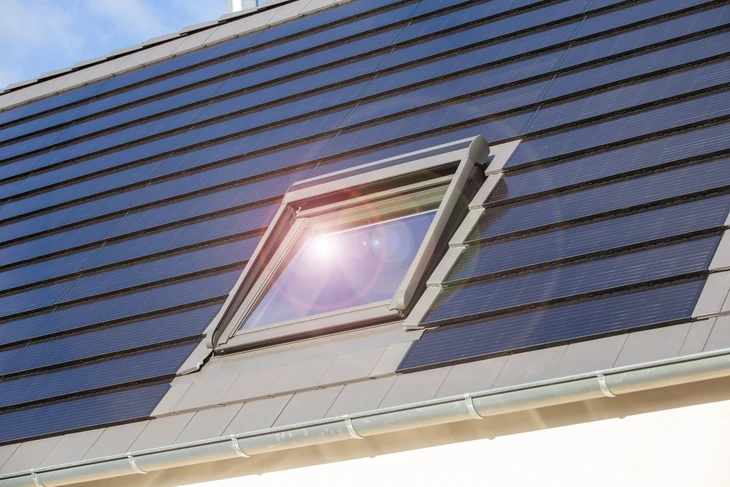 Fenêtre de toit sur une maison individuelle avec des tuiles solaires