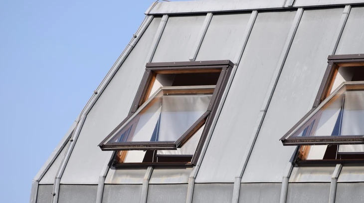 Façade extérieure d'un bâtiment moderne avec fenêtres de toit ouvertes intégrées dans une toiture métallique