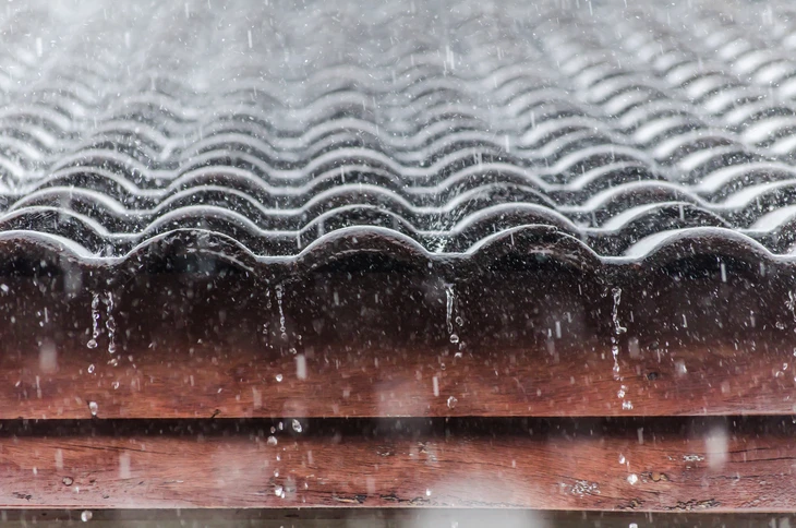 Extérieur sous forte pluie, gouttière métallique ondulée installée sur structure bois