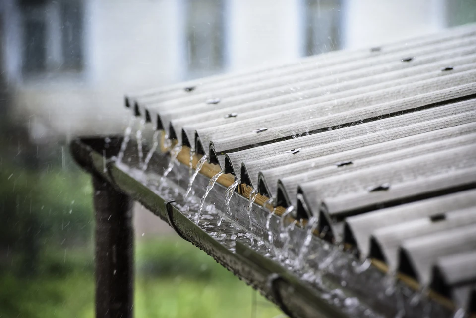 Scène extérieure sous la pluie montrant l'évacuation d'eau pluviale depuis une toiture