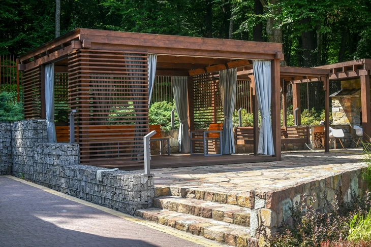 Aménagement extérieur contemporain avec pergola en bois exotique à lames orientables et rideaux blancs