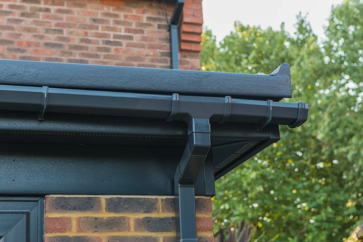 Extérieur résidentiel avec système de gouttières en PVC anthracite installé sur toiture