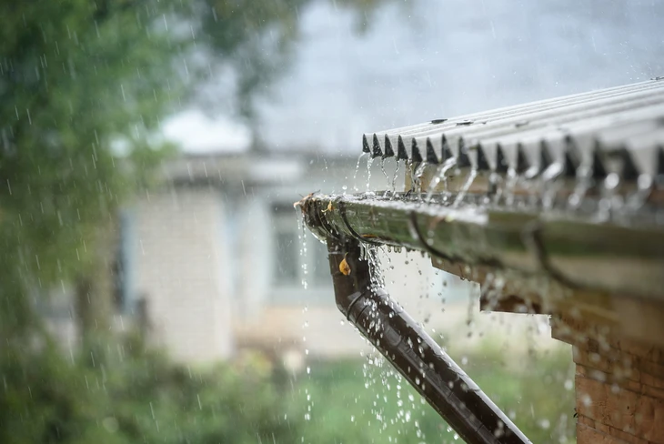 Scène extérieure sous la pluie montrant l'évacuation d'eau pluviale depuis une toiture