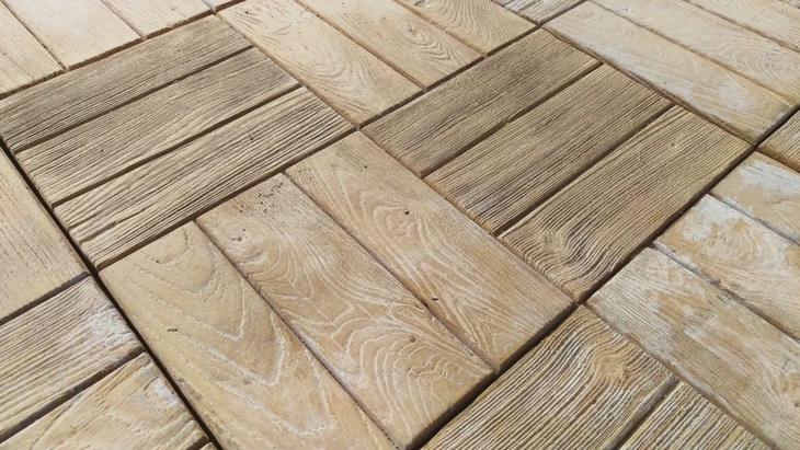 Terrasse extérieure avec dalles en bois naturel disposées en motif chevrons alternés