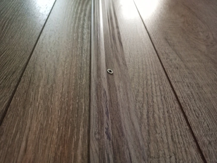 Plancher en bois composite gris installé en extérieur, lames rainurées avec joints de dilatation visibles
