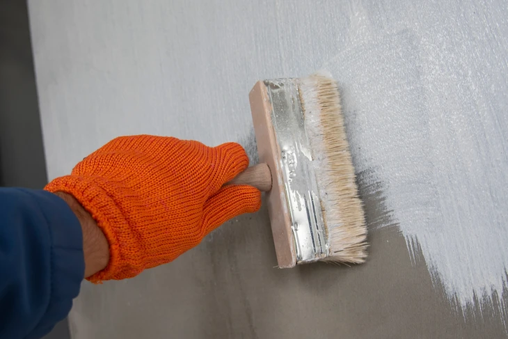 Un ouvrier applique de la peinture imperméabilisante sur le mur