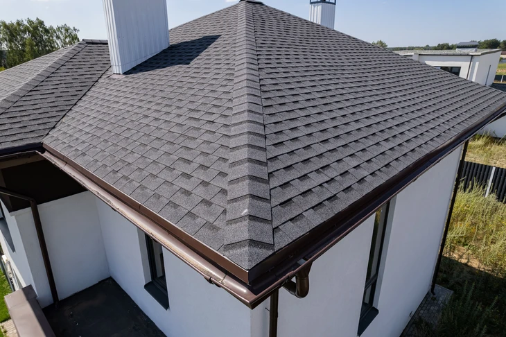 Vue aérienne d'une toiture résidentielle moderne avec bardeaux d'asphalte gris installés selon un motif en rangées décalées