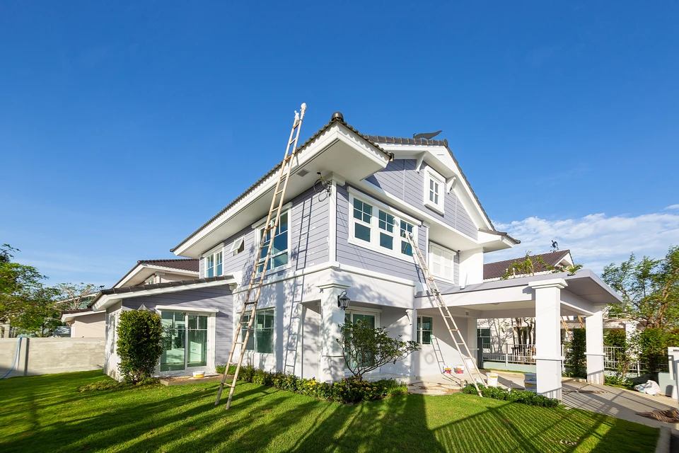 Ouvriers effectuant des travaux de couverture sur une maison moderne à deux étages avec bardage gris et blanc