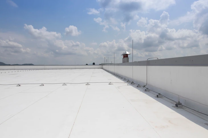 Toiture terrasse industrielle en membrane blanche étanche sous ciel nuagé