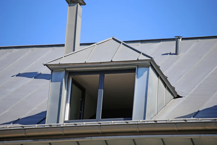 Extérieur d'une maison avec toiture métallique grise à joints debout et lucarne ouverte