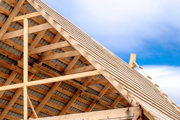 Chantier de construction d'une charpente en bois sous ciel bleu nuageux