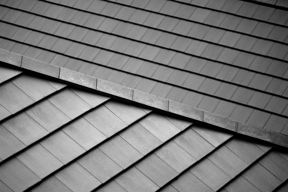 Toiture résidentielle avec tuiles plates en ardoise naturelle grise disposées en rangées chevauchantes