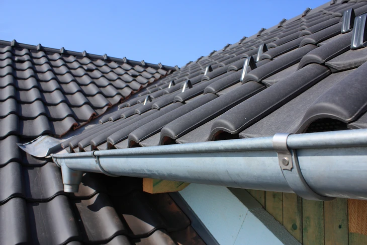 Extérieur d'une maison avec toiture en tuiles mécaniques grises sous ciel bleu