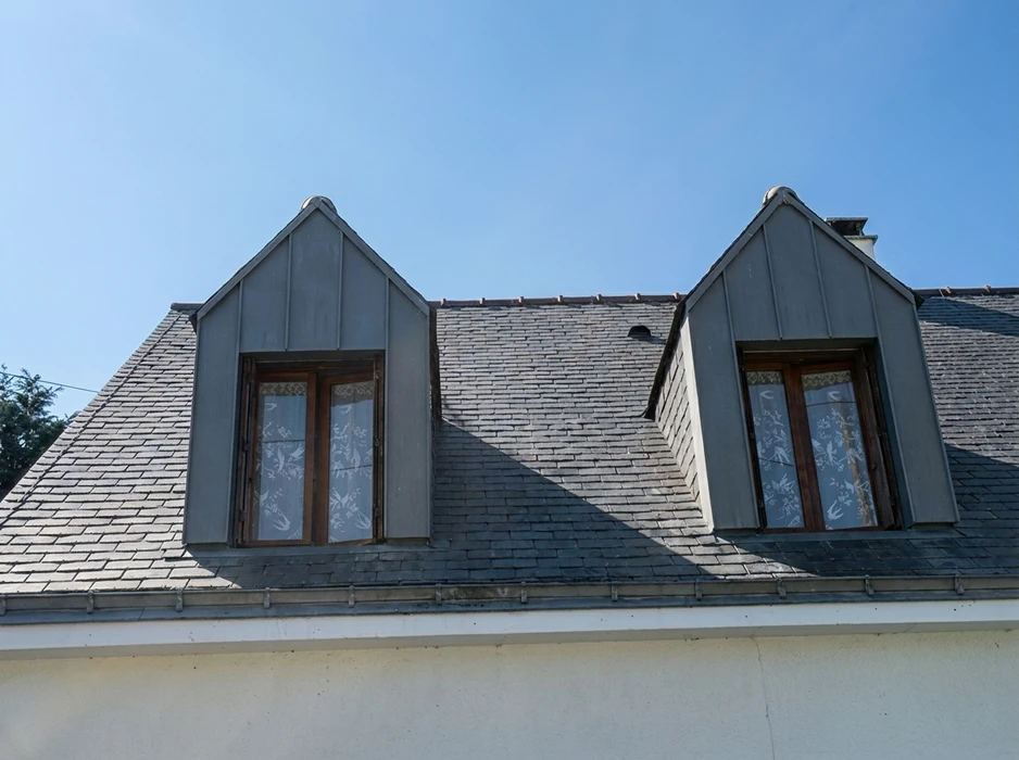 Toiture ancienne en tuiles d'argile rouge fortement endommagée avec nombreuses tuiles manquantes et déplacées