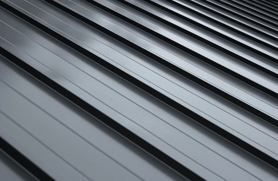 Photographie d'une toiture de maison résidentielle montrant clairement des éléments de zinc : gouttières en zinc, chéneaux, et détails de zinguerie autour d'une fenêtre de toit ou d'une cheminée. La toiture peut être en ardoise, tuiles ou zinc, mais les éléments de zinguerie doivent être visibles et constituer le point focal de l'image. L'angle de prise de vue doit permettre de bien voir le travail artisanal de la couverture et de la zinguerie.